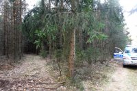 zdjęcie wykonane w lesie. Na drzewie wiszący sznurek, obok radiowóz z otwartymi bocznymi drzwiami
