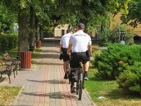 Policjanci w patrolu rowerowym patrolują park miejski.