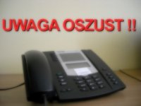 Telefon stacjonarny na stole i napis UWAGA OSZUST.
