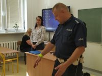 Policjant prezentuje sposób noszenia odblasków