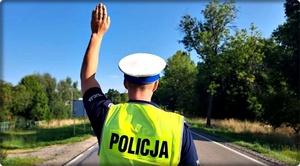 Policjant na drodze podnosi rękę.
